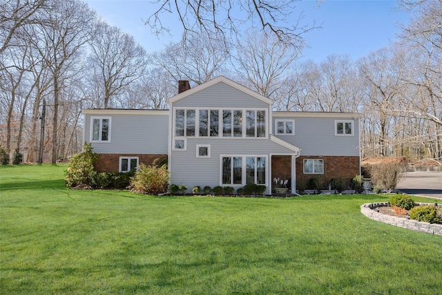 view of front of home with brick siding, a chimney, and a front lawn