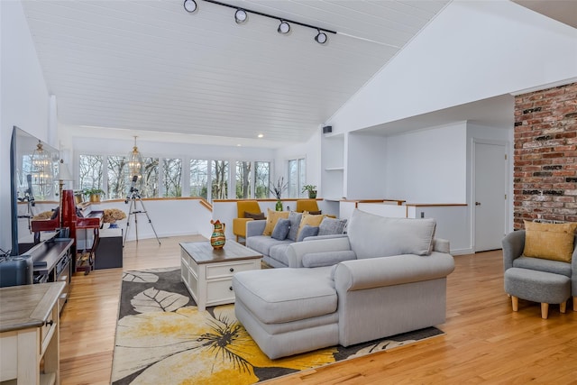 living area with a wealth of natural light, high vaulted ceiling, an inviting chandelier, and light wood finished floors