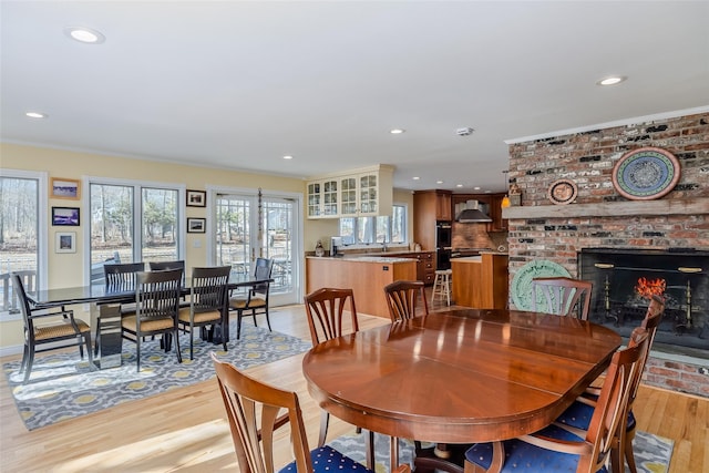 dining space with recessed lighting, a brick fireplace, and light wood finished floors