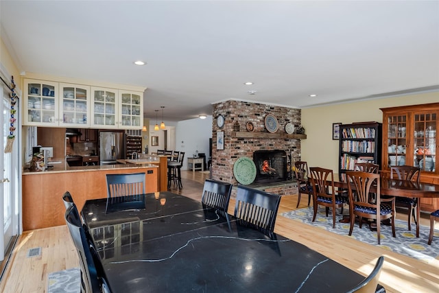 dining room featuring recessed lighting, a fireplace, visible vents, and light wood finished floors