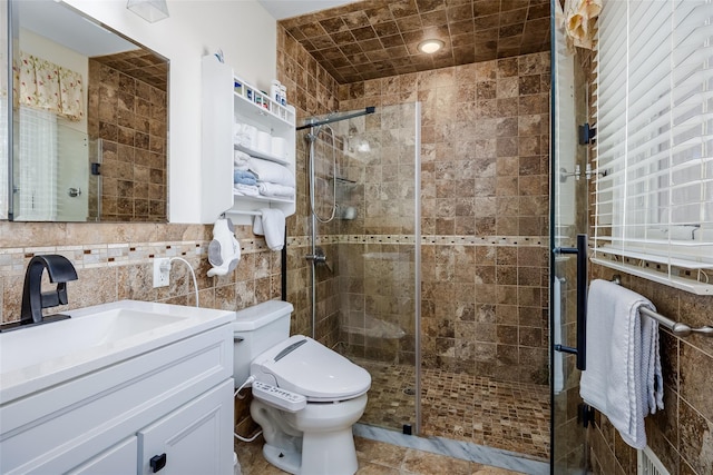 bathroom with a shower stall, tile walls, vanity, and toilet