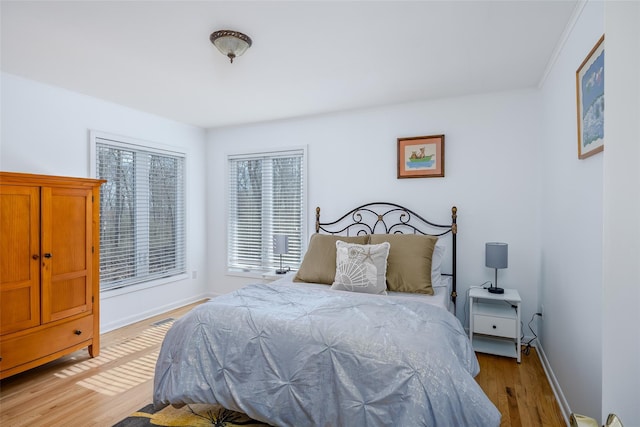 bedroom featuring light wood-style flooring, baseboards, and ornamental molding