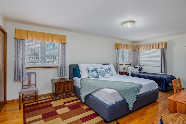 bedroom featuring baseboards, multiple windows, and wood finished floors