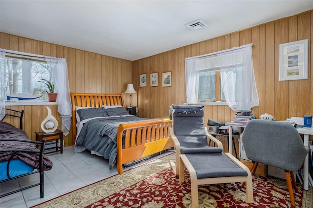 bedroom featuring tile patterned flooring, visible vents, and wood walls