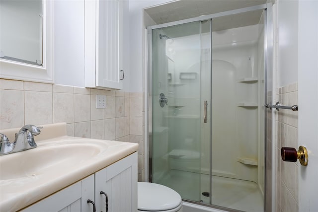 bathroom with toilet, tile walls, a stall shower, and vanity