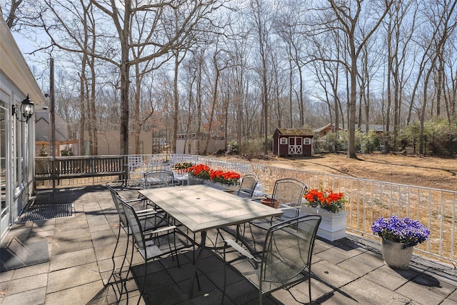 view of patio with an outbuilding, outdoor dining space, and a storage unit