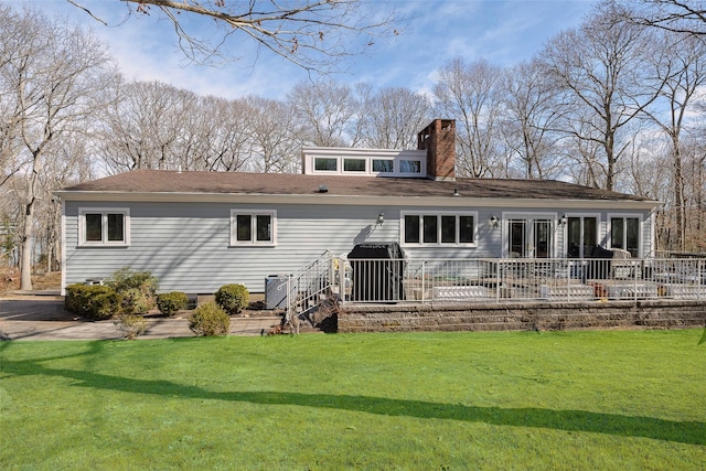 back of house with a lawn, a patio, a chimney, and roof with shingles