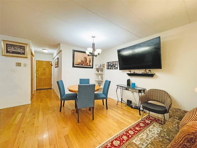 dining room with a chandelier, light wood-style flooring, and baseboards