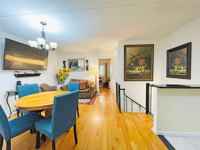 dining space featuring a chandelier, baseboards, and light wood-style floors