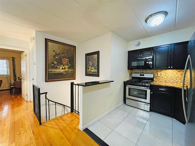 kitchen featuring tasteful backsplash, baseboards, light wood-style floors, black appliances, and dark cabinets