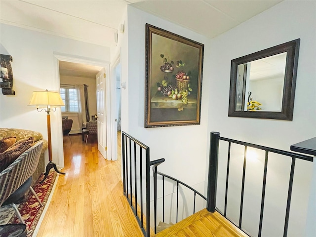 corridor with an upstairs landing and light wood-style flooring