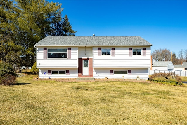 raised ranch featuring a front lawn and a shingled roof