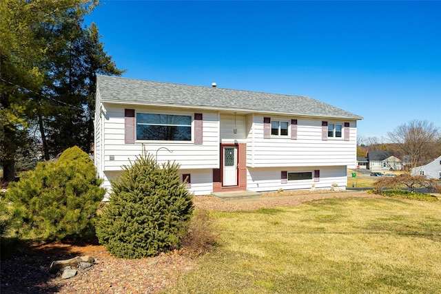 split foyer home with roof with shingles and a front yard