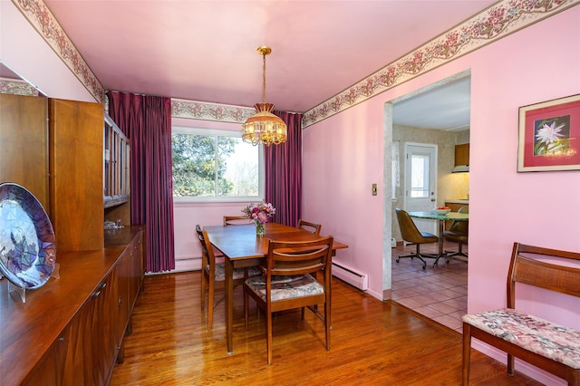 dining space with a baseboard heating unit, an inviting chandelier, wood finished floors, and a healthy amount of sunlight