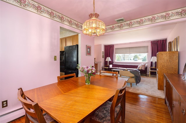 dining space featuring visible vents, wood finished floors, baseboard heating, and a chandelier