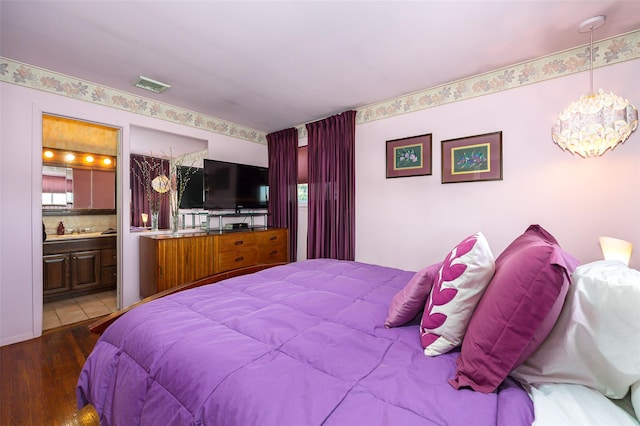 bedroom with visible vents, ensuite bath, and wood finished floors