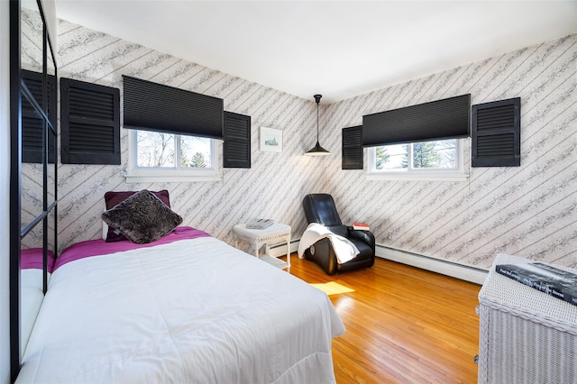 bedroom with multiple windows, wood finished floors, and a baseboard radiator