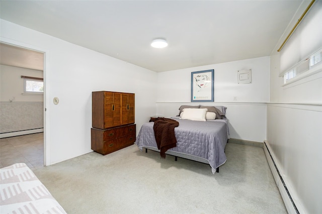 bedroom featuring a baseboard heating unit and light colored carpet