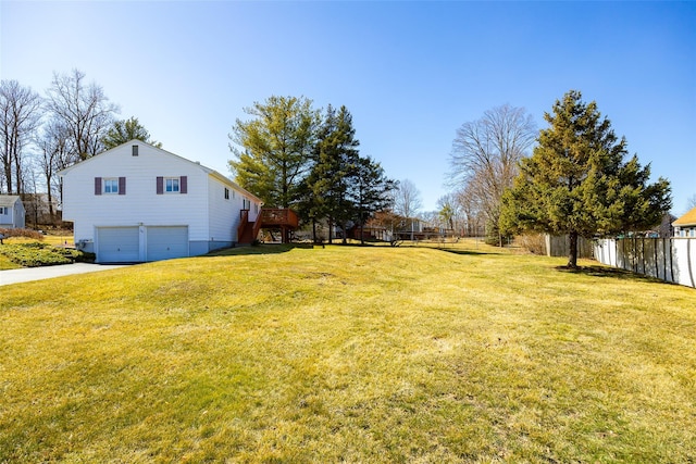 view of yard featuring concrete driveway, a deck, an attached garage, and fence