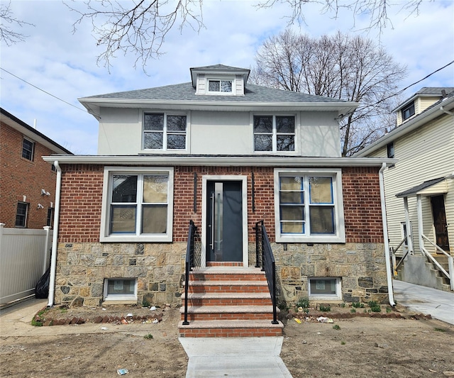 american foursquare style home with stucco siding, stone siding, and fence