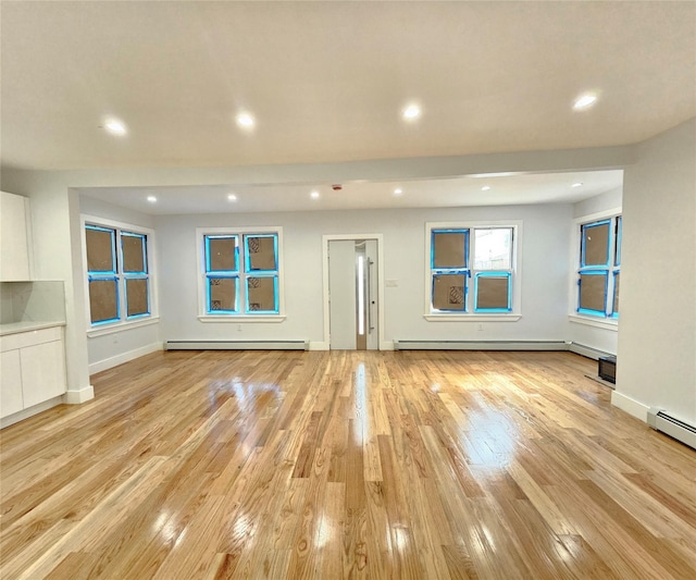 unfurnished living room with recessed lighting, a baseboard radiator, baseboards, and light wood-style flooring