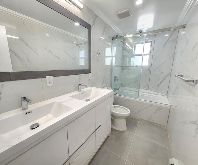 full bathroom with a sink, bath / shower combo with glass door, tile walls, and toilet