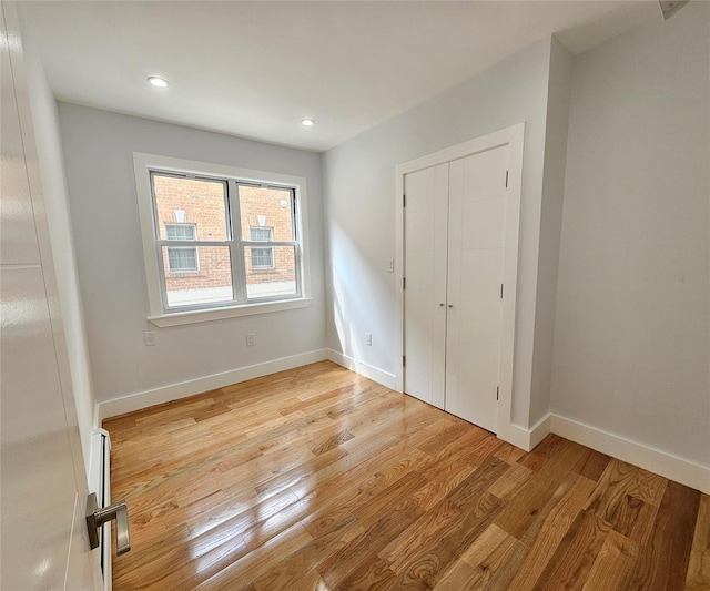 unfurnished bedroom featuring light wood-style flooring, recessed lighting, baseboards, and a closet