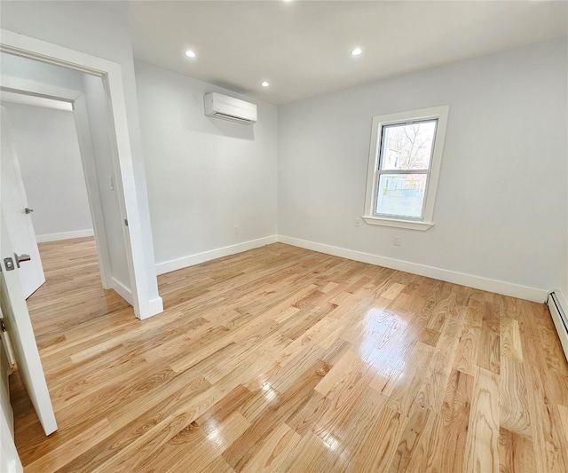 empty room with recessed lighting, baseboards, an AC wall unit, and light wood-style flooring