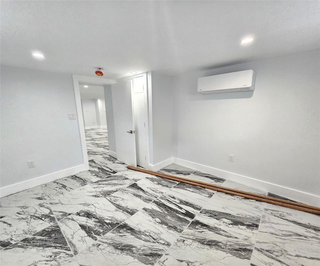 empty room featuring an AC wall unit, recessed lighting, baseboards, and marble finish floor