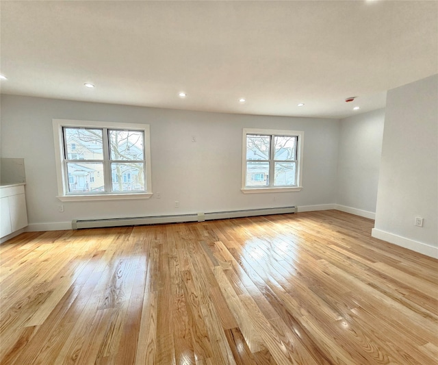 spare room with recessed lighting, a baseboard heating unit, baseboards, and light wood-style flooring