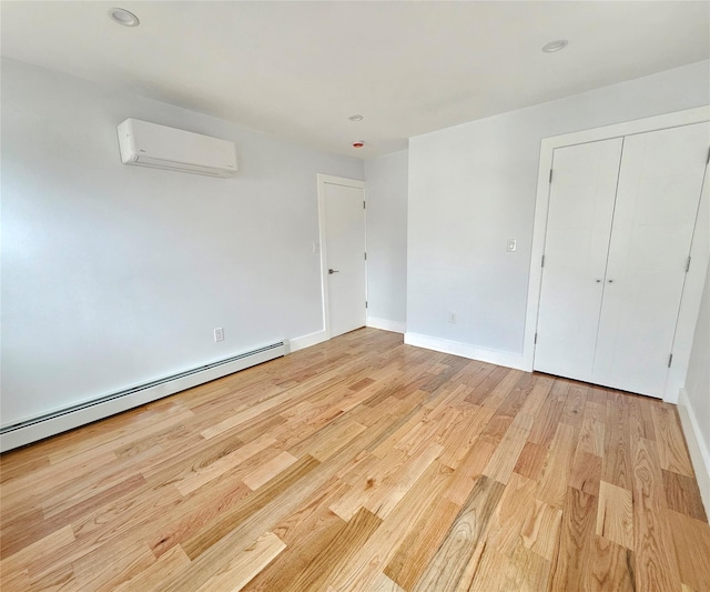 empty room featuring light wood finished floors, an AC wall unit, a baseboard heating unit, and baseboards