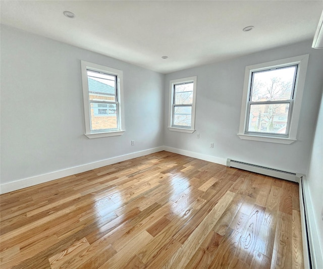 spare room with light wood finished floors, a baseboard heating unit, baseboards, recessed lighting, and a baseboard radiator