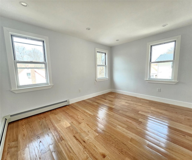 spare room featuring light wood-type flooring, a baseboard heating unit, and baseboards