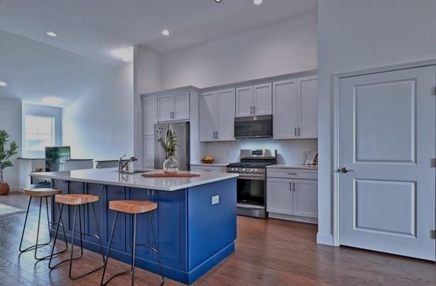 kitchen featuring a breakfast bar, a center island with sink, a sink, appliances with stainless steel finishes, and light countertops