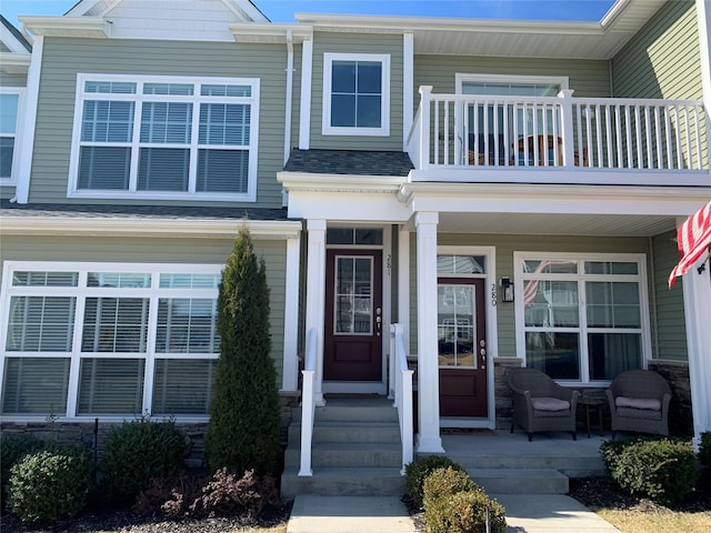 view of front of property featuring a balcony, covered porch, and a shingled roof