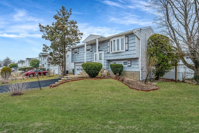 split foyer home featuring a front yard, fence, and aphalt driveway