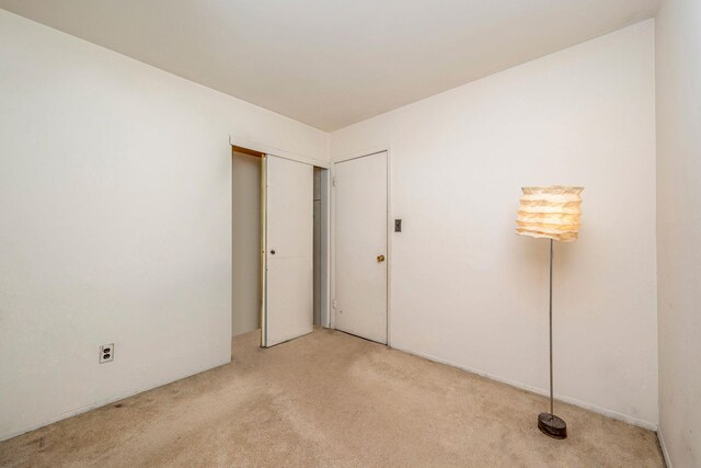 unfurnished bedroom featuring a closet and light colored carpet