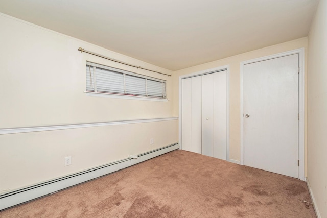 unfurnished bedroom with a baseboard heating unit, carpet, and a closet