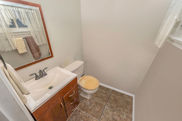 half bath with baseboards, toilet, and vanity