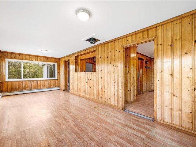 empty room featuring wood finished floors, wood walls, and a baseboard heating unit