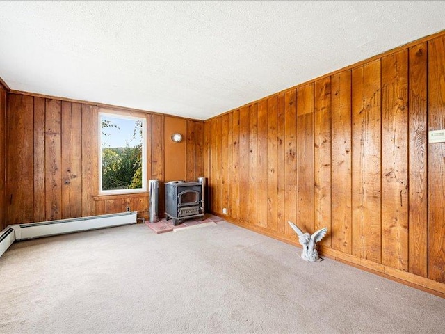 spare room with a wood stove, carpet floors, wood walls, and a textured ceiling