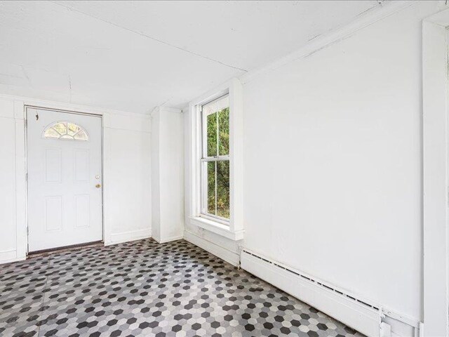 foyer featuring baseboard heating, plenty of natural light, and baseboards