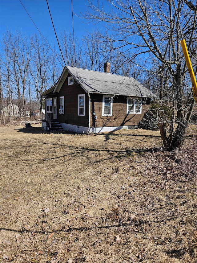 view of home's exterior featuring a chimney and roof with shingles
