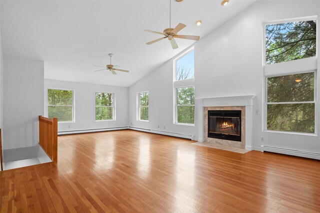 unfurnished living room featuring high vaulted ceiling, a ceiling fan, wood finished floors, a fireplace, and a baseboard heating unit