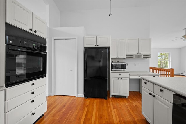 kitchen featuring black appliances, light countertops, white cabinets, and light wood-style floors