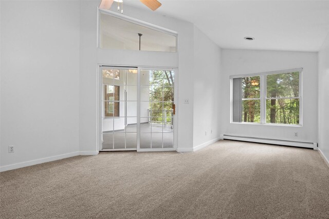 empty room featuring baseboard heating, vaulted ceiling, plenty of natural light, carpet floors, and ceiling fan