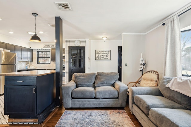 living area with visible vents, dark wood-style flooring, and crown molding