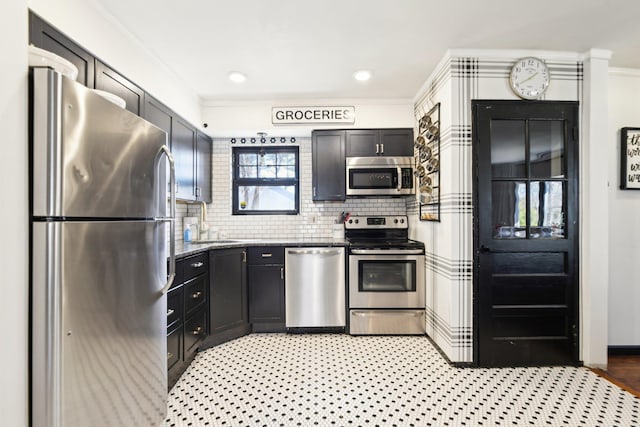 kitchen with a sink, dark stone counters, appliances with stainless steel finishes, crown molding, and decorative backsplash