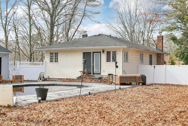 rear view of house with a chimney and fence