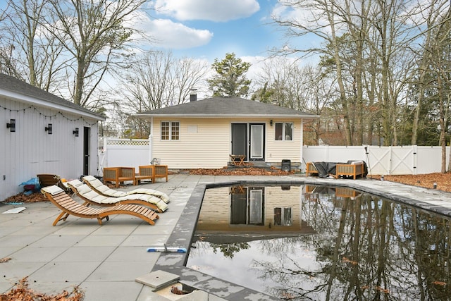 back of house featuring a fenced in pool, a fenced backyard, an outbuilding, a patio, and a gate